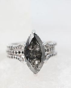 a white diamond ring sitting on top of a snow covered ground with the stone in it's center