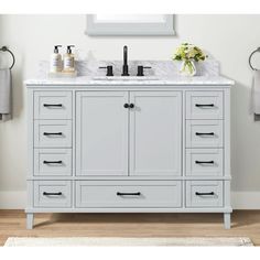 a white bathroom vanity with marble top and two black faucets on the sink