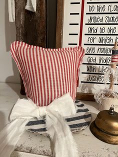 a red and white striped pillow sitting on top of a table next to a bell