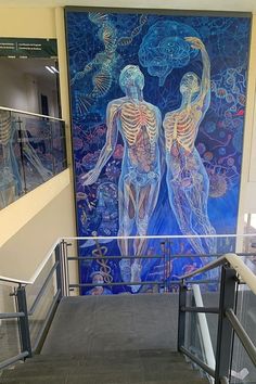 a large painting on the side of a building next to a stair case with glass railings