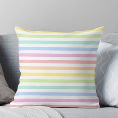 a colorful striped pillow sitting on top of a couch next to a gray pillow case