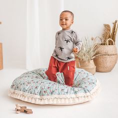 a young boy standing on top of a round pillow