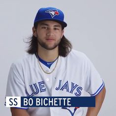 a baseball player is posing for a photo with his hat on and long hair in the air