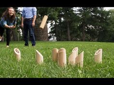 two people are playing in the grass with some wooden objects that look like bats and stumps