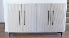 a white cabinet sitting on top of a hard wood floor next to a stair case