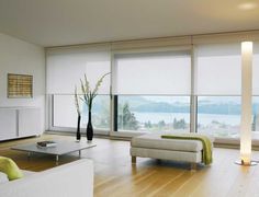 a living room filled with white furniture and large windows overlooking the water's edge