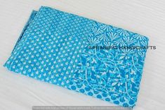 a blue and white patterned cloth laying on top of a bed