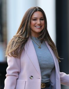 a woman with long hair wearing a pink coat