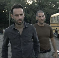 two men standing in front of a school bus