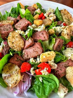 a white plate topped with meat and veggies on top of a wooden table