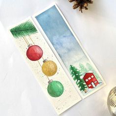 two bookmarks with christmas ornaments on them next to a pine cone and fir tree