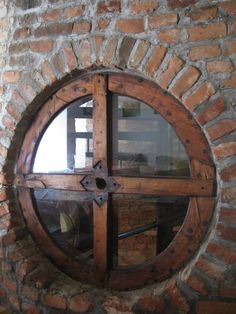 a round window in the side of a brick wall with wood trimmings on it