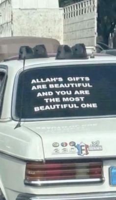 a white car parked in front of a building with a sign on the back window