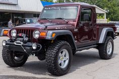 a maroon jeep is parked in a parking lot