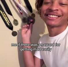 a young man smiling next to some medals and a wall with the words me if there was an award for getting mad easily