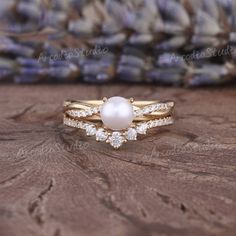 an image of a pearl and diamond ring on a wooden surface with beads in the background