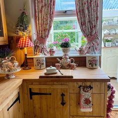 the kitchen is decorated with pink flowers and teapots on the counter, along with potted plants