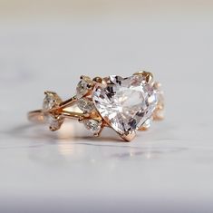 This heart shaped pink sapphire engagement ring is one of a kind. It features 3.5ct natural sapphire set in unique diamond setting in 14k rose gold. The Moonlight sapphire, is almost colourless, diamond-like, with a ting of peach, mauve or ice blue, that changes constantly, depending on the lightening! Excellent cut thet radiates tons of sparkles. This ring will definitely steal her heart :) Very beautiful and delicate - this ring is so feminine. Rose gold diamond setting works perfectly to high Heart Shaped Sapphire Ring, Heart Cut Ring With Rose Cut Diamonds, 14k Rose Gold Heart Cut Jewelry For Wedding, Rose Gold Rings With Heart-cut Rose Diamonds, Rose Gold Heart Cut Rings With Rose Cut Diamonds, Pink Gold Heart Cut Wedding Ring, Engagement Rings Heart, Heart Shaped Engagement Ring, Heart Shaped Wedding Rings