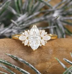 an engagement ring with a pear shaped diamond surrounded by smaller pears on top of a piece of wood