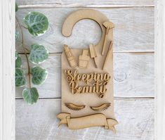 a cutting board with the words sleeping beauty on it next to a plant and scissors