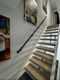 a staircase with wooden handrails and paintings on the wall