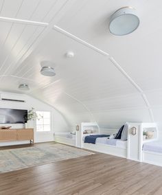 an attic bedroom with white walls and wood flooring is pictured in this image, there are two beds on either side of the room