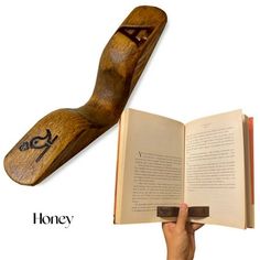 an open book with the word honey written on it and a hand holding a wooden bookmark