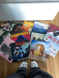 a person's feet on the floor surrounded by various album covers