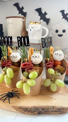 three small pots filled with fruit and vegetables sitting on top of a wooden cutting board