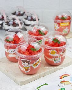 four plastic cups filled with strawberries on top of a table