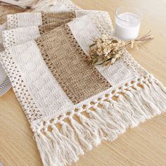 a table topped with a white and brown blanket next to a glass of milk on top of a wooden table