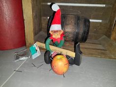 an apple sitting on top of a wooden chair next to a hammer and an elf's hat