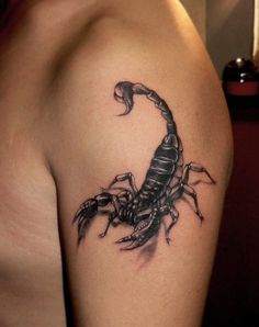 a scorpion tattoo on the back of a woman's shoulder, with black ink