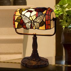 a stained glass lamp sitting on top of a table next to a potted plant