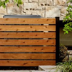 a wooden fence next to a brick wall and potted plant in front of it