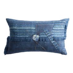 a blue pillow with an embroidered design on the front and back, sitting on a white background