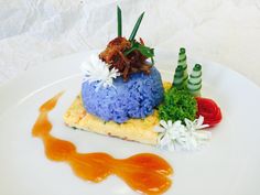 a white plate topped with food covered in blue and orange sauce next to other items