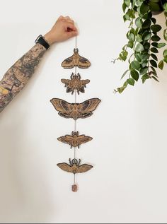 a person holding up a wall hanging with moths on it's sides and hands