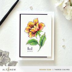 a card with a flower on it next to a pen and some watercolor pencils