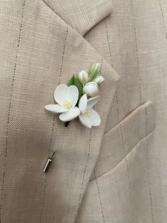 a boutonniere with white flowers pinned to the lapel of a suit