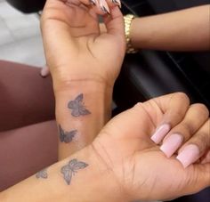 two people holding hands with tattoos on them