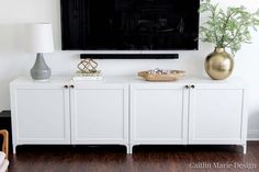 a flat screen tv mounted to the side of a white cabinet in a living room