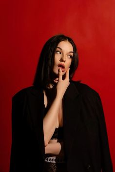 a woman is posing with her hand on her mouth while wearing a black blazer