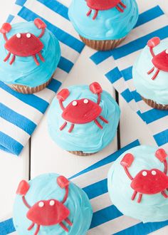 cupcakes decorated with blue frosting and red crabs on striped paper napkins