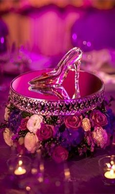 a pink wedding ring sitting on top of a table with flowers and candles around it