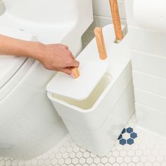 a person is cleaning a toilet with two wooden brushes and soap dispensers