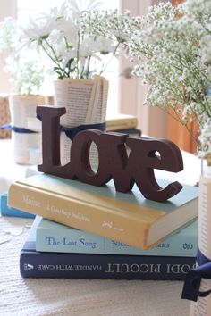 a stack of books sitting on top of a table next to a vase filled with flowers