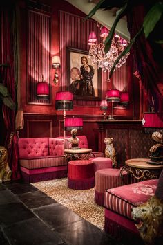 a living room filled with red couches and chairs next to a chandelier