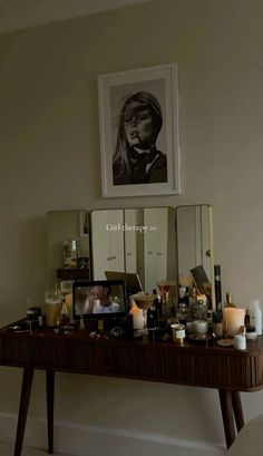 a wooden table topped with lots of candles next to a framed photo on the wall