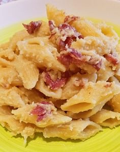 a yellow plate topped with pasta covered in cheese and meat sauce on top of a table